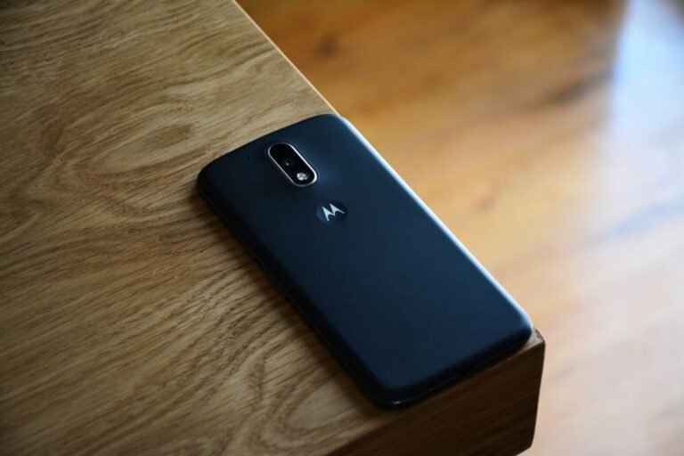 A black smartphone lying on a wooden table. Exact location is not confirmed.