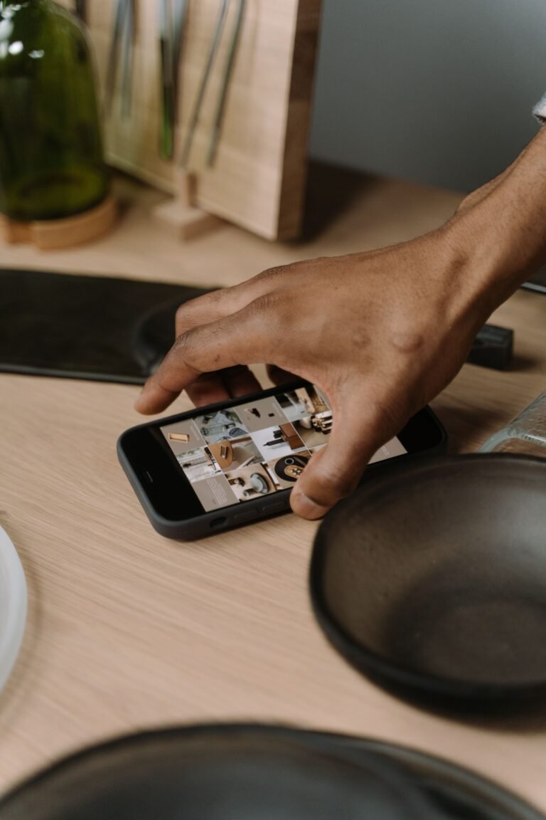 A person using a smartphone on a table beside household items. Exact location is not confirmed.